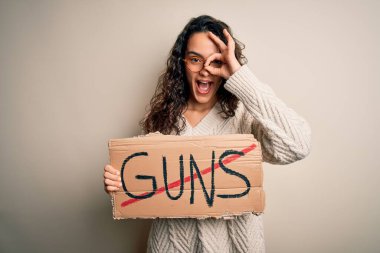 Kıvırcık saçlı genç bir kadın yasak silahlarla pankart tutuyor. Mutlu yüzlü, gülümseyen bir mesajı var. Tamam.
