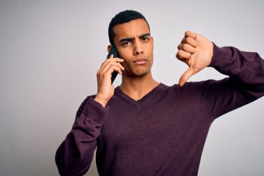 Genç ve yakışıklı Afro-Amerikalı bir adam akıllı telefondan kızgın bir suratla konuşuyor. Negatif işaret baş parmakları aşağıda, reddedilme konsepti reddedildi.