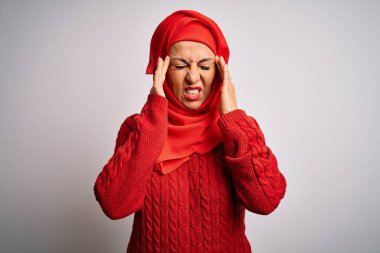 Orta yaşlı esmer kadın, geleneksel Müslüman tesettüre bürünmüş, izole edilmiş beyaz arka plan ve baş ağrısı çeken bir el. Migren ağrısı..
