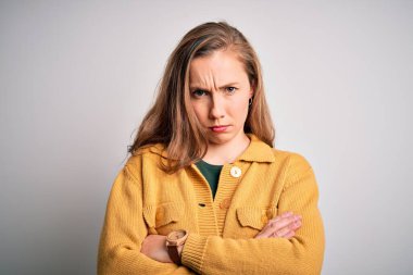 Genç, güzel, sarışın bir kadın izole edilmiş beyaz arka plan kuşkucu ve gergin kolları çaprazlanmış yüz ifadesini tasvip etmeyen bir süveter giyiyor. Negatif kişi.