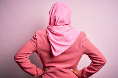 Genç Afrikalı Afro kadın, izole edilmiş pembe arka planda Müslüman başörtüsü takıyor geriye bakıyor kolları vücudunda.