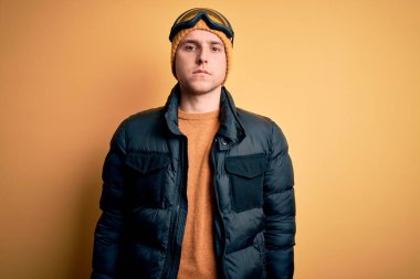 Kış için şapka, palto ve kayak gözlüğü takan yakışıklı beyaz bir adam. Ve kar havası, yüzünde ciddi bir ifadeyle rahatladı. Basit ve doğal bir şekilde kameraya bakıyorsun..