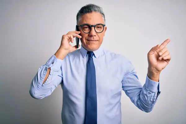 중년의 잘생긴 백발의 사업가 스마트폰으로 얘기하는 행복하게 손가락으로 가리키고 있습니다 — 스톡 사진