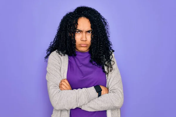 紫の背景にカジュアルなスウェットシャツを着た若いアフリカ系アメリカ人のスポーティな女性は懐疑的で緊張し 両腕を組んで顔に不承認の表現 負の人 — ストック写真