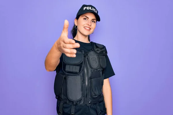 年轻的女警察身穿紫色背景的防弹背心制服 微笑友好地握手致意和欢迎 成功的业务 — 图库照片