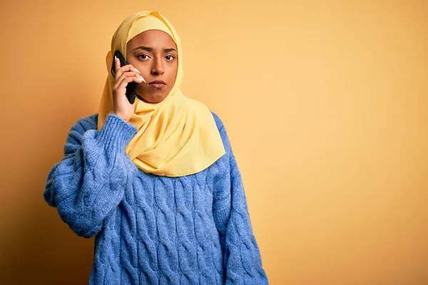 イスラム教徒のヒジャーブを身に着けているアフリカ系アメリカ人女性は 真剣に考えてスマートフォンで話す自信のある表情で会話をしています — ストック写真