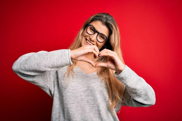 Jovem Mulher Loira Bonita Vestindo Suéter Óculos Sobre Fundo Vermelho — Fotografia de Stock