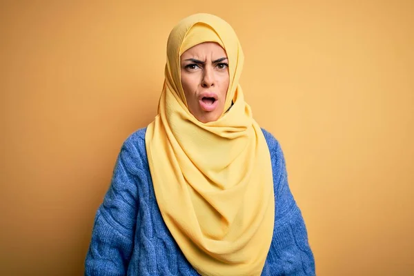 若いです美しいですブルネットムスリム女性身に着けていますArab Hijab上の隔離された黄色の背景で衝撃的な顔 懐疑的で皮肉 驚きますオープン口 — ストック写真