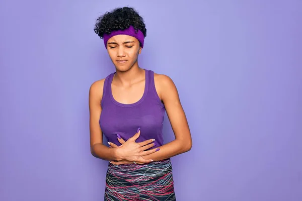美丽的非洲裔美国女人穿着休闲运动服 背带紫色背景 手放在肚子上 因为消化不良 痛苦的疾病感觉不舒服 阿切概念 — 图库照片
