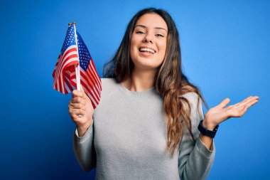 Genç, güzel, vatansever kadın elinde Amerikan bayrağıyla 4 Temmuz 'u kutluyor. Çok mutlu ve heyecanlı. Kazanan ifade zaferi kutluyor.