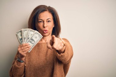 Orta yaşlı esmer kadın, elinde bir dolar banknotla izole edilmiş arka planda kamerayı işaret ediyor. Ve sen, el işareti, ön taraftan pozitif ve kendinden emin bir hareket.