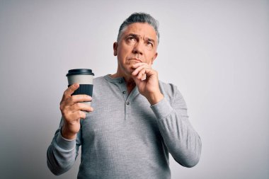 Orta yaşlı, yakışıklı, gri saçlı, kahve içen, izole edilmiş beyaz arka planda, ciddi yüzlü soru soran, kafası karışık bir adam.
