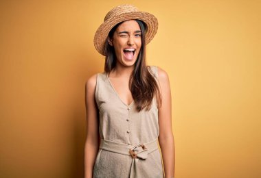 Genç, güzel, esmer bir kadın tatilde. Sıradan bir elbise giyiyor ve şapkasını takıyor. Seksi bir ifadeyle kameraya bakıyor..