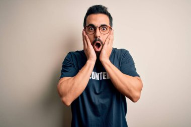 Beyaz arka planda gönüllü mesajı olan sakallı yakışıklı bir adam. Korkmuş ve şok olmuş.