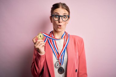 Kırmızı arka planda madalyalar takan genç, güzel, kızıl saçlı bir kadın. Şaşırmış bir yüzle korkmuş ve korku ifadesinden heyecanlanmış.