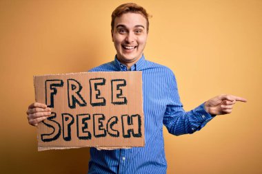 Genç ve yakışıklı kızıl saçlı adam özgürlük istiyor özgür konuşma mesajıyla pankartı tutuyor mutlu bir gülümsemeyle el ve parmak kenarı işaret ediyor