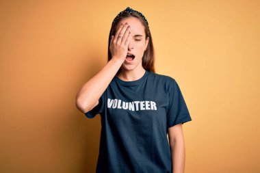 Gönüllü tişört giyen genç ve güzel bir kadın sarı arka planda gönüllü olarak esneme hareketleri yapıyor. Yarı yüz, yarı göz, yarı ağız, yarı el esneme hareketleri yapıyor. Yüzüm acıyor..