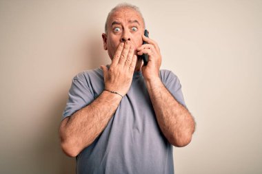 Orta yaşlı, ağarmış bir adam beyaz arka planda telefonla konuşuyor. Ağzı kapalı, utancından ağzı açık, korkunun ifadesi, sessizlikten korkan, gizli bir konsept.