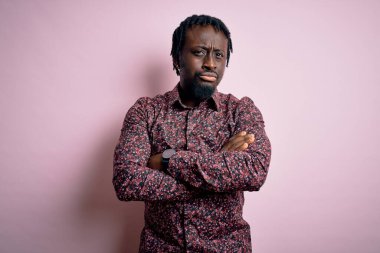 Genç, yakışıklı, Afro-Amerikalı bir adam pembe arka planda duran, kuşkucu ve gergin kollarını kavuşturmuş, tasvip etmeyen bir ifade takınıyor. Negatif kişi.
