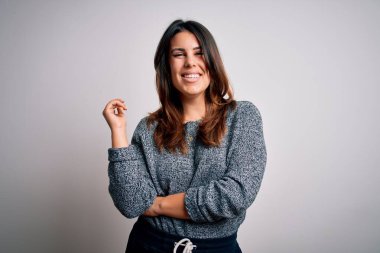 Genç ve güzel esmer kadın mutlu ve kendinden emin gülümsüyor. Yüzünde tebessümle dikilip, izole beyaz arka planda günlük süveter giyiyorsun.