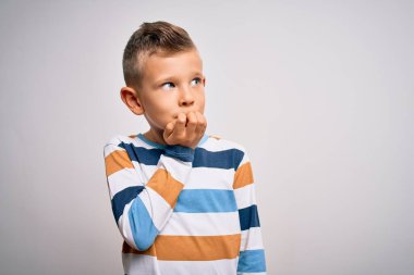 İzole edilmiş arka planda çizgili tişört giymiş, elleri ağızdan tırnak yerken gergin ve gergin görünen mavi gözlü küçük beyaz çocuk. Endişe sorunu.