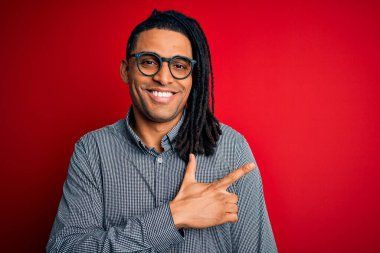 Rastgele gömlek ve gözlük takan, yüzünde mutlu ve doğal bir ifadeyle el ve parmaklarıyla yüzünü gösteren gülümseyen yakışıklı Afro-Amerikalı genç adam.