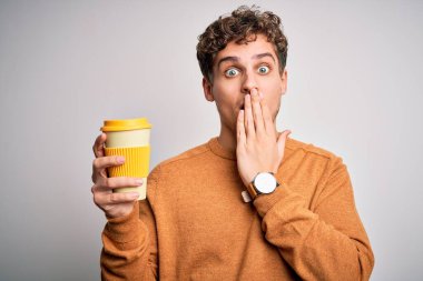 Sarışın, kıvırcık saçlı, beyaz arka planda duran kahve fincanı içen genç bir adam. Ağzı kapalı, utancından ağzı açık, korkudan dehşete düşmüş, sessizlikten korkan, gizli bir konsept.