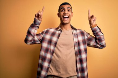 Genç, yakışıklı, Afro-Amerikalı bir adam sarı arka planda dikilmiş şaşkın şaşkın, parmaklarıyla işaret ediyor ve kollarını kaldırıyordu..