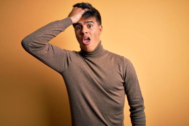 Sarıya boyanmış sarı arka plan üzerine balıkçı yaka kazak giyen genç yakışıklı bir adam hata için el ele tutuşarak şaşırdı. Hatayı hatırla. Unuttum, kötü hafıza konsepti.