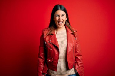 İzole edilmiş arka planda kırmızı deri ceket giyen güzel bir kadın. Mutlu ve havalı bir gülümsemesi var. Şanslı kişi..