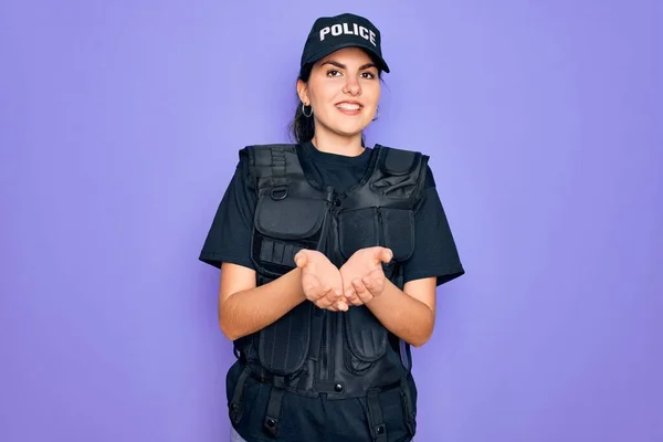 Young police woman wearing security bulletproof vest uniform over purple background Smiling with hands palms together receiving or giving gesture. Hold and protection