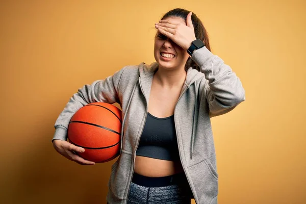 Young Beautiful Brunette Sportswoman Holding Basketball Ball Yellow Background Stressed — Stock Photo, Image