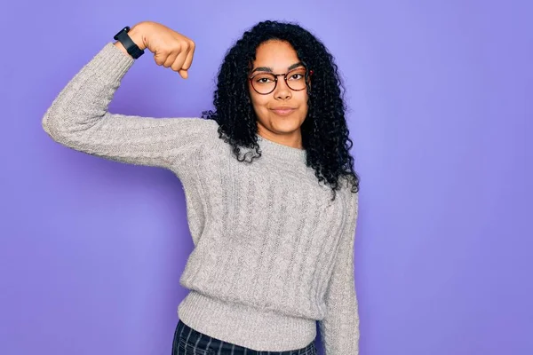 年轻的非洲裔美国女人 身穿宽松的毛衣 戴着紫色背景的眼镜 强壮的手臂肌肉 自信而自豪 — 图库照片