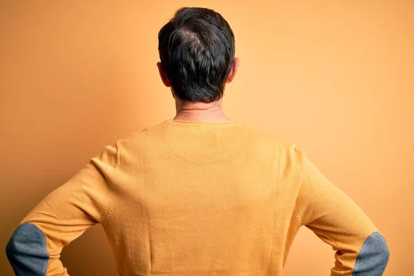 中年人白发男子 身穿休闲衫 眼镜戴在孤立的黄色背景上 背对着身体 向后看去 — 图库照片