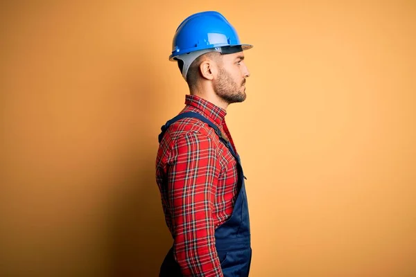 年轻的建筑工人身穿建筑制服 头戴安全帽 头戴黄底 面带微笑 轻松自然地摆姿势 — 图库照片