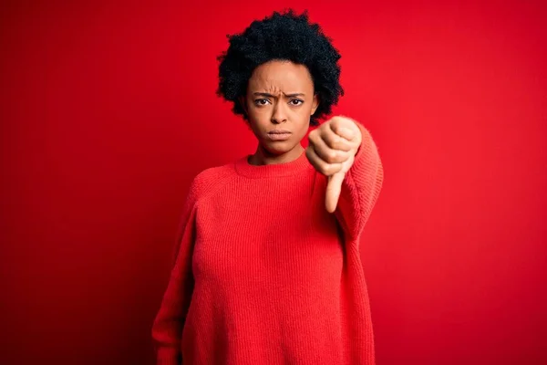 カジュアルセーターを身に着けている巻き毛を持つ若い美しいアフリカ系アメリカ人アフロ女性は 親指ダウンジェスチャーで不満と否定を示して怒っている 悪い表現 — ストック写真