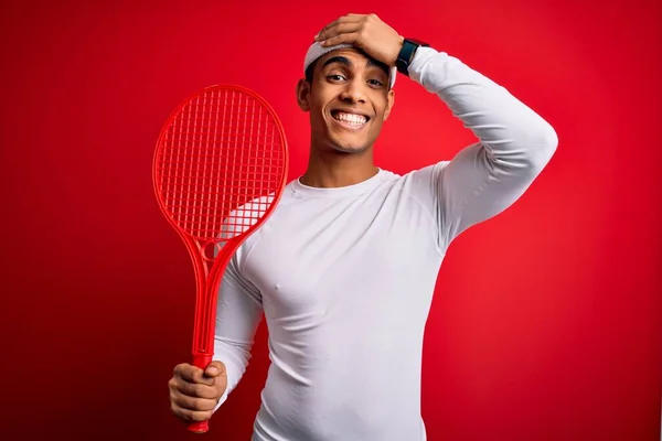 若いハンサムなアフリカ系アメリカ人のスポーツマンは 頭の上に手で強調赤の背景にラケットを使用してテニスをプレイし 恥と驚きの顔でショックを受け 怒りと不満 恐怖と過ちへの動揺 — ストック写真