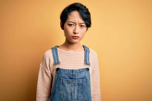Young Beautiful Asian Girl Wearing Casual Denim Overalls Isolated Yellow — Stock Photo, Image