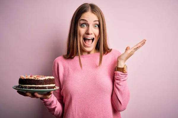 Junge Schöne Rothaarige Frau Hält Geburtstagstorte Über Isoliertem Rosa Hintergrund — Stockfoto