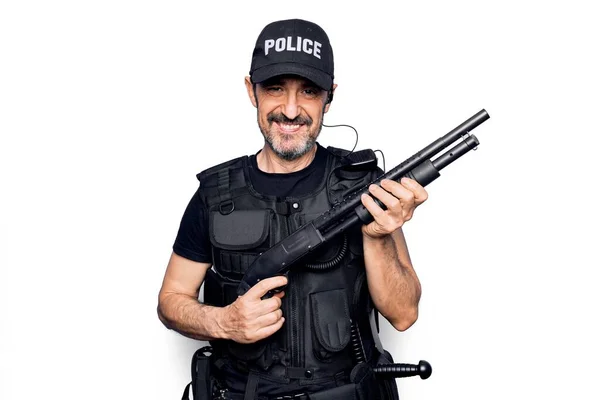 中世のハンサムな警官を着て警察制服と防弾ベストを保持散弾銃見て正と幸せな立ちと笑顔で自信を持って笑顔示す歯 — ストック写真