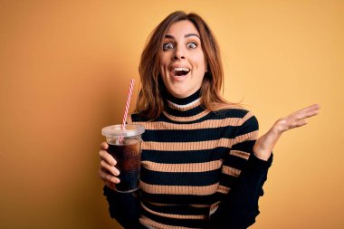 Genç, güzel, esmer bir kadın pipetle bardakta kola içiyor. Çok mutlu ve heyecanlı. Kazanan ifade zaferi büyük bir gülümsemeyle kutluyor ve ellerini kaldırıyor.