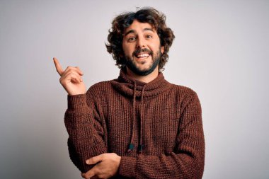 Sakallı, sıradan bir süveter giyen, yüzünde kocaman bir gülümsemeyle kameraya bakan, eli ve parmağı olan genç yakışıklı bir adam..