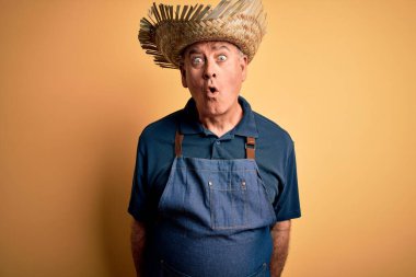 Sarı arka plan üzerinde önlük ve şapka takan orta yaşlı çiftçi. Şaşırtıcı bir ifade, korku ve heyecanlı bir yüz ifadesiyle dehşete düşmüş ve şok olmuş..