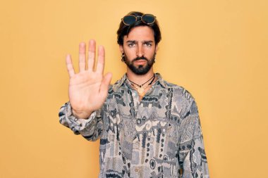 Hippi tarzı giyinen ve güneş gözlüğü takan yakışıklı İspanyol bohem adam avucunun içi gibi şarkı söylemeyi kesiyor. Yüzünde olumsuz ve ciddi bir jest olan uyarı ifadesi.