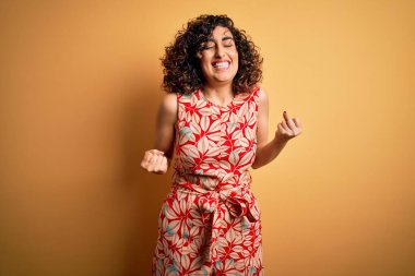 Genç ve güzel kıvırcık Arap kadın tatilde. Çiçekli bir elbise ve güneş gözlüğü takıyor. Çok mutlu ve heyecanlı. Kutlama konsepti.