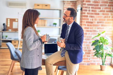 Mutlu ve kendinden emin gülümseyen iki orta yaşlı iş adamı. Gülümseyerek konuşmak ofiste kahve içmek.