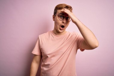 İzole edilmiş pembe arka planda duran sıradan tişörtlü, genç, yakışıklı, kızıl saçlı bir adam hata için el ele tutuşarak şaşırdı. Hatayı hatırla. Unuttum, kötü hafıza konsepti.