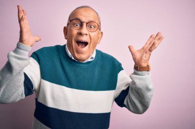 Üst düzey yakışıklı adam, günlük süveter ve gözlük takıp pembe arka planda çılgınca kutlama yapıyor ve kollarını kaldırıp heyecanla haykırarak başarıyı kutluyor. Kazanan konsept