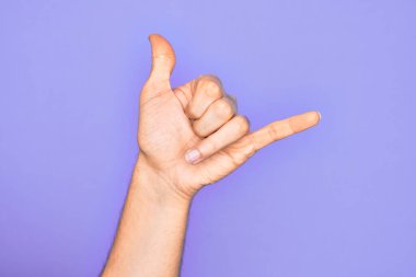 İzole edilmiş mor arka planda parmaklarını gösteren Kafkas genci el hareketi, Hawaii Shaka selamlama hareketi, telefon ve iletişim sembolü