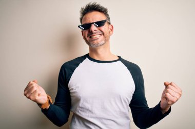 Genç yakışıklı adam beyaz arka planda komik bir eşkıya hayatı takıyor. Mutlu ve heyecanlı bir şekilde kollarını kaldırıp, gülümseyip başarı için bağırıyor. Kutlama konsepti.